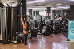Un gimnasio con diferentes máquinas de ejercicio, incluyendo una barra de dominadas y equipo de levantamiento de pesas.
