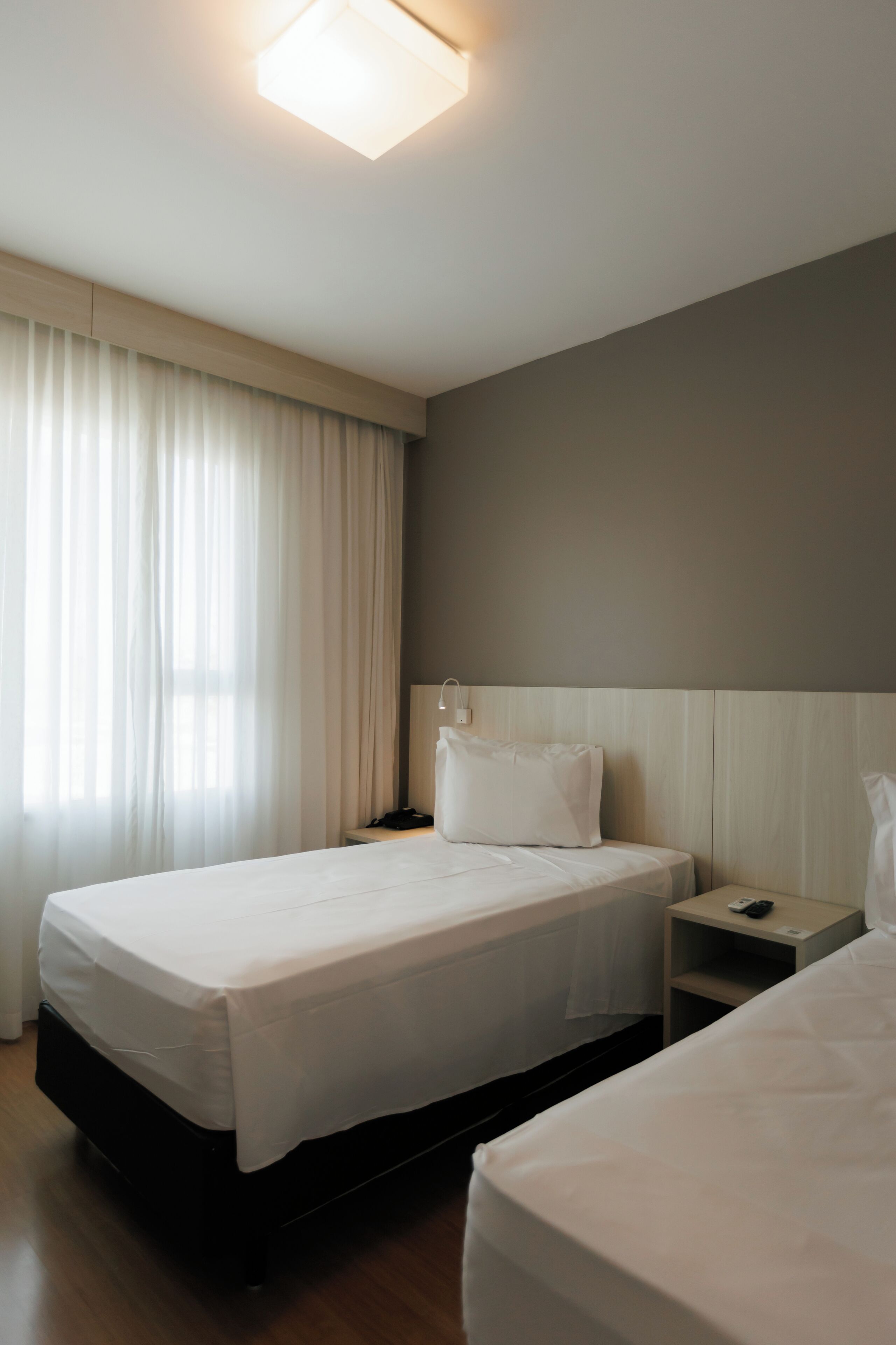 A hotel room with a bed, bedside table, and a nightstand.
