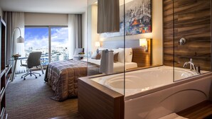 A modern hotel room with a large window, a private bathroom with a bathtub, a desk with a chair, and a bed with a view of the city. - Gorrion Hotel Istanbul (Istanbul)