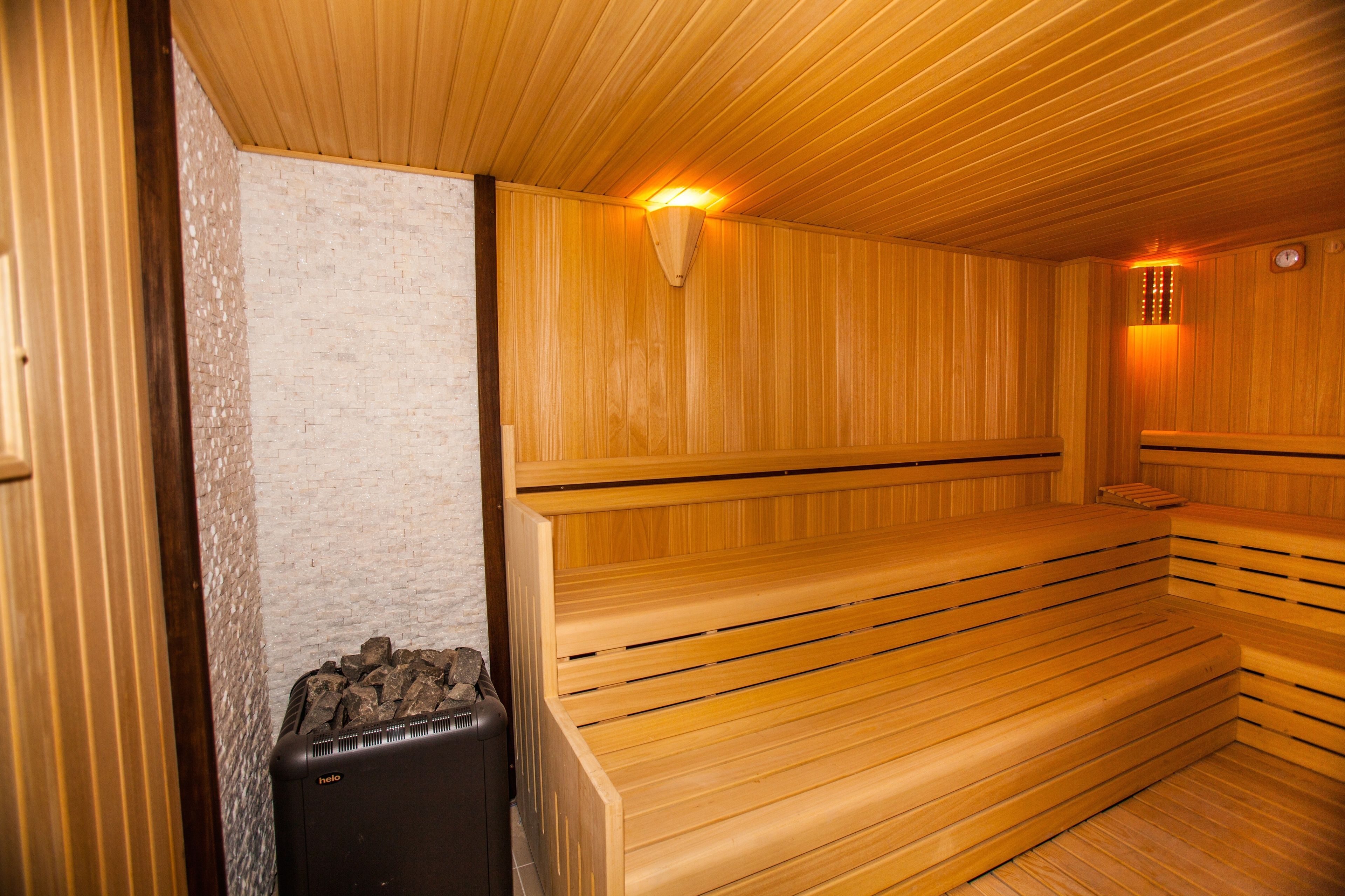 A sauna with wooden benches and a wall-mounted heater.