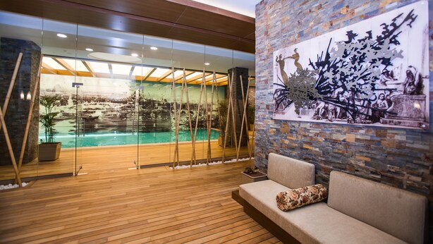A modern indoor pool area with a wooden floor, a seating area with a cushioned bench, and a mural on the wall. - Gorrion Hotel Istanbul (Istanbul)
