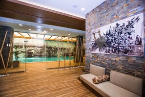 A modern indoor pool area with a wooden floor, a seating area with a cushioned bench, and a mural on the wall. - Gorrion Hotel Istanbul (Istanbul)