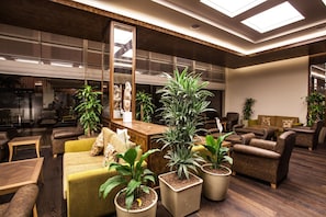 Uma área de estar moderna com sofás, poltronas e plantas em vasos.