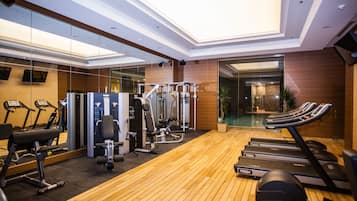Une salle de sport moderne équipée de tapis de course, d’appareils de musculation et dotée d’un plancher en bois.