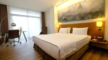 Une chambre d’hôtel avec un grand lit, un bureau, une chaise et un tableau représentant une tour accroché au mur.