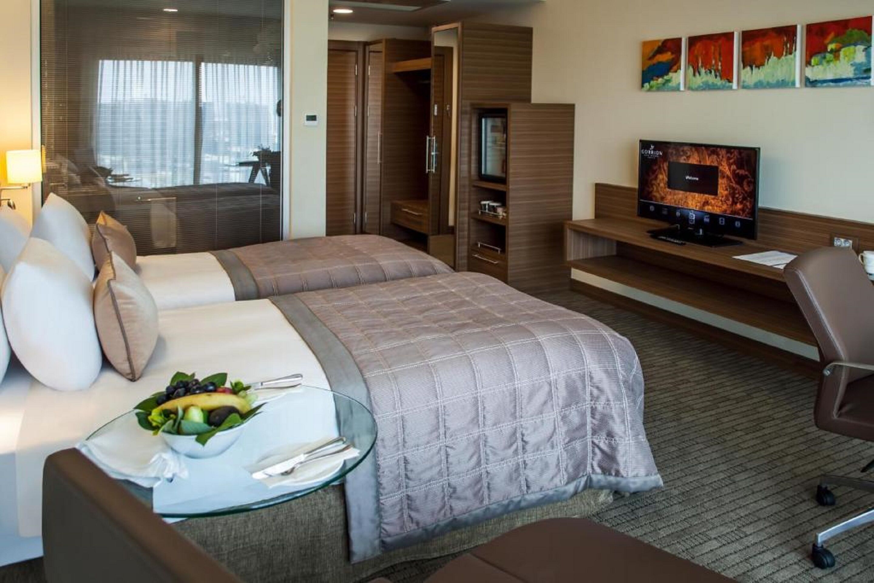 Ein Hotelzimmer mit Bett, Schreibtisch mit Computer, Fernseher und einer Sitzecke mit Glastisch.