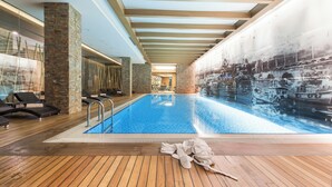An indoor swimming pool with wooden flooring, lounge chairs, and a mural of boats on the wall. - Gorrion Hotel Istanbul (Istanbul)