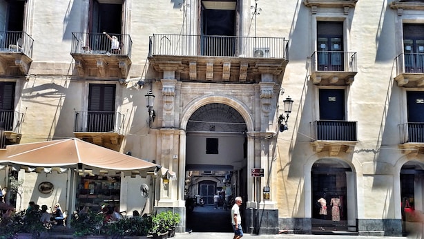 Un edificio histórico con detalles arquitectónicos ornamentales, incluyendo un arco central y varios balcones.