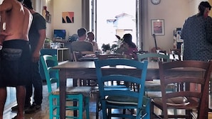Comedor con techo alto que presenta patrones decorativos, mesas y sillas de madera, y vistas a través de un acceso abierto.