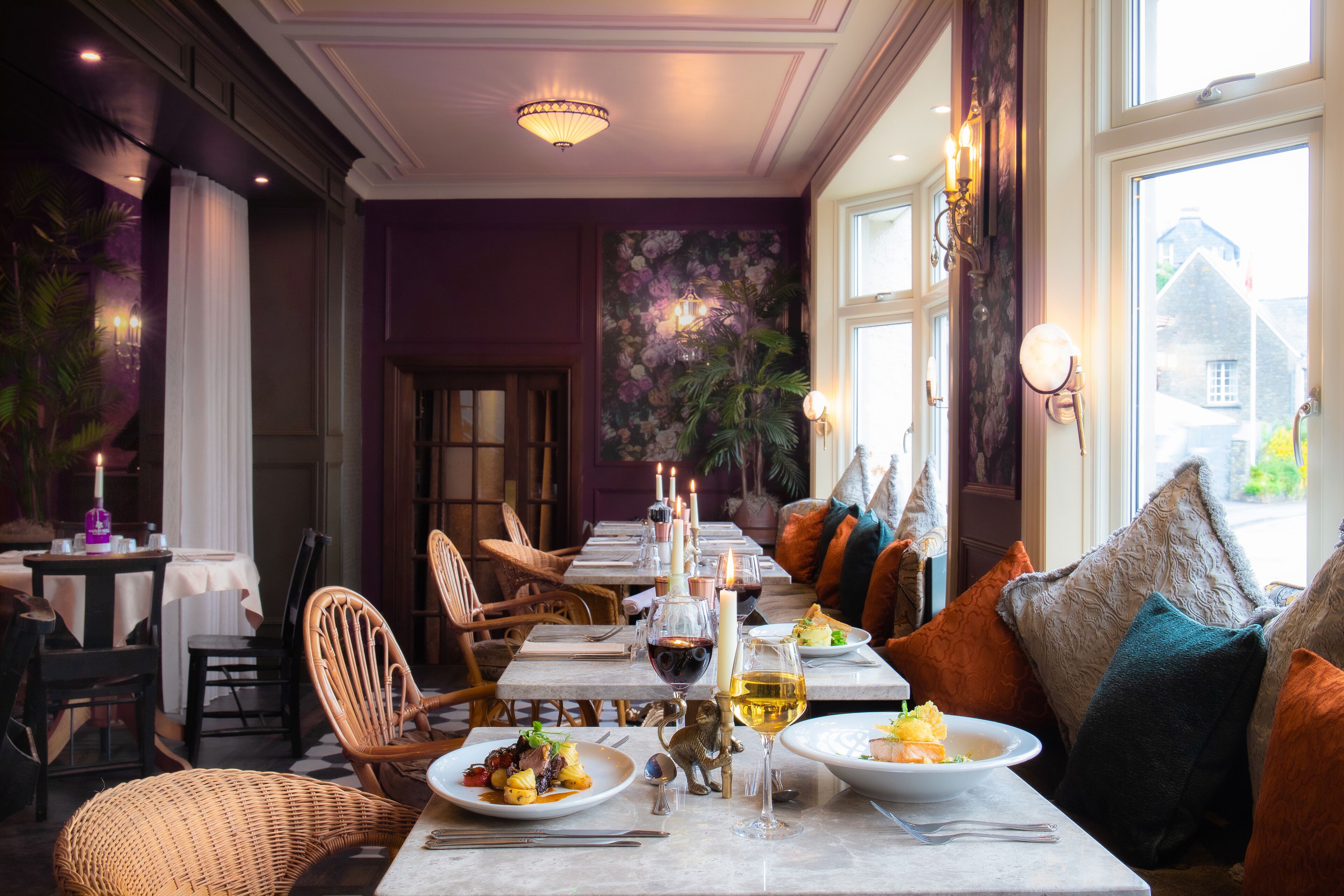 A dining area with tables set for two, featuring a variety of dishes and wine glasses.