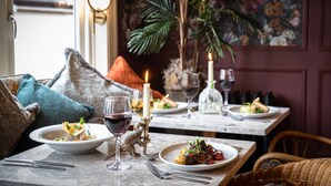 Une table à manger avec des assiettes remplies de nourriture, des verres à vin et une bougie.