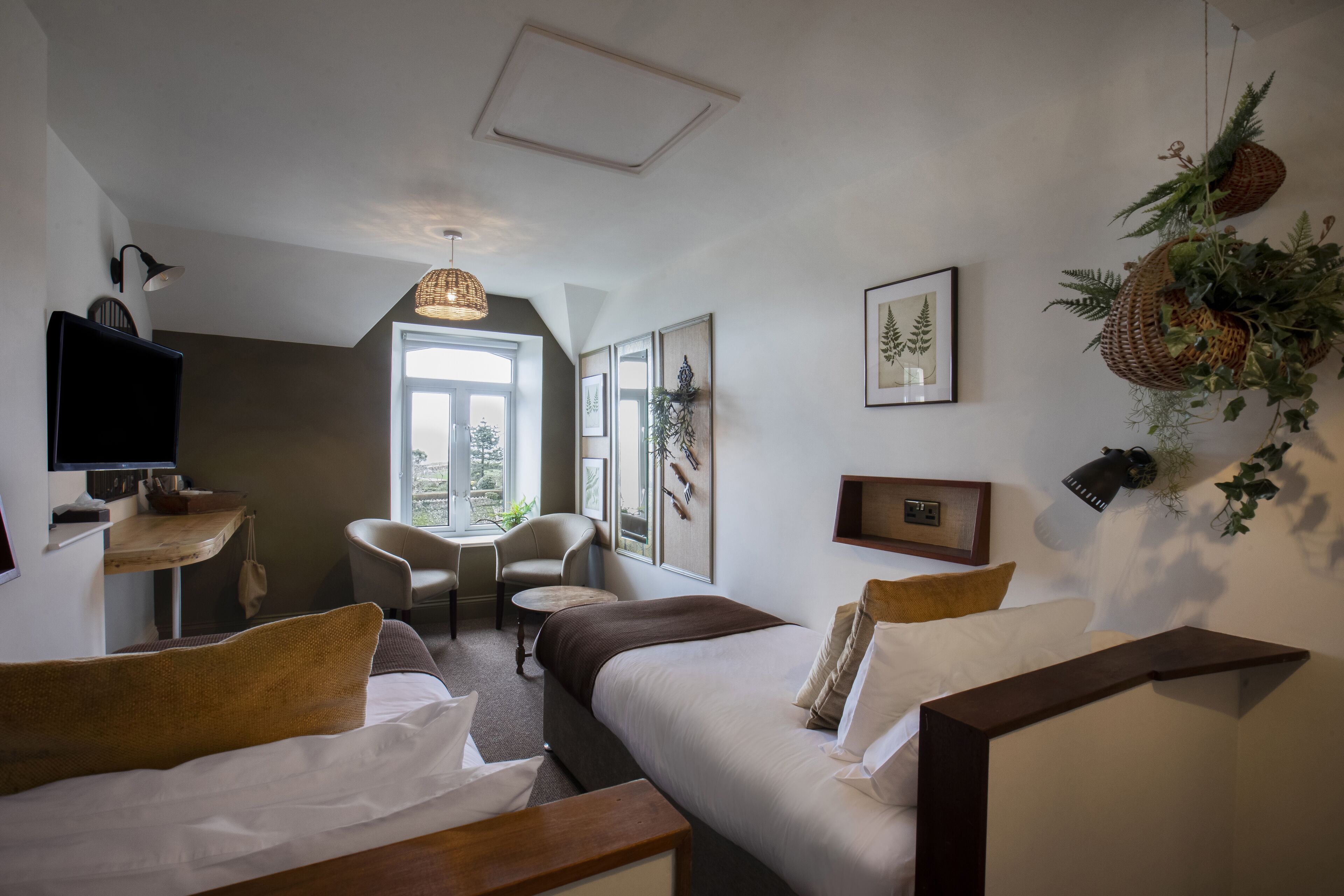 Habitación de hotel con dos camas, un escritorio, una silla y una ventana.