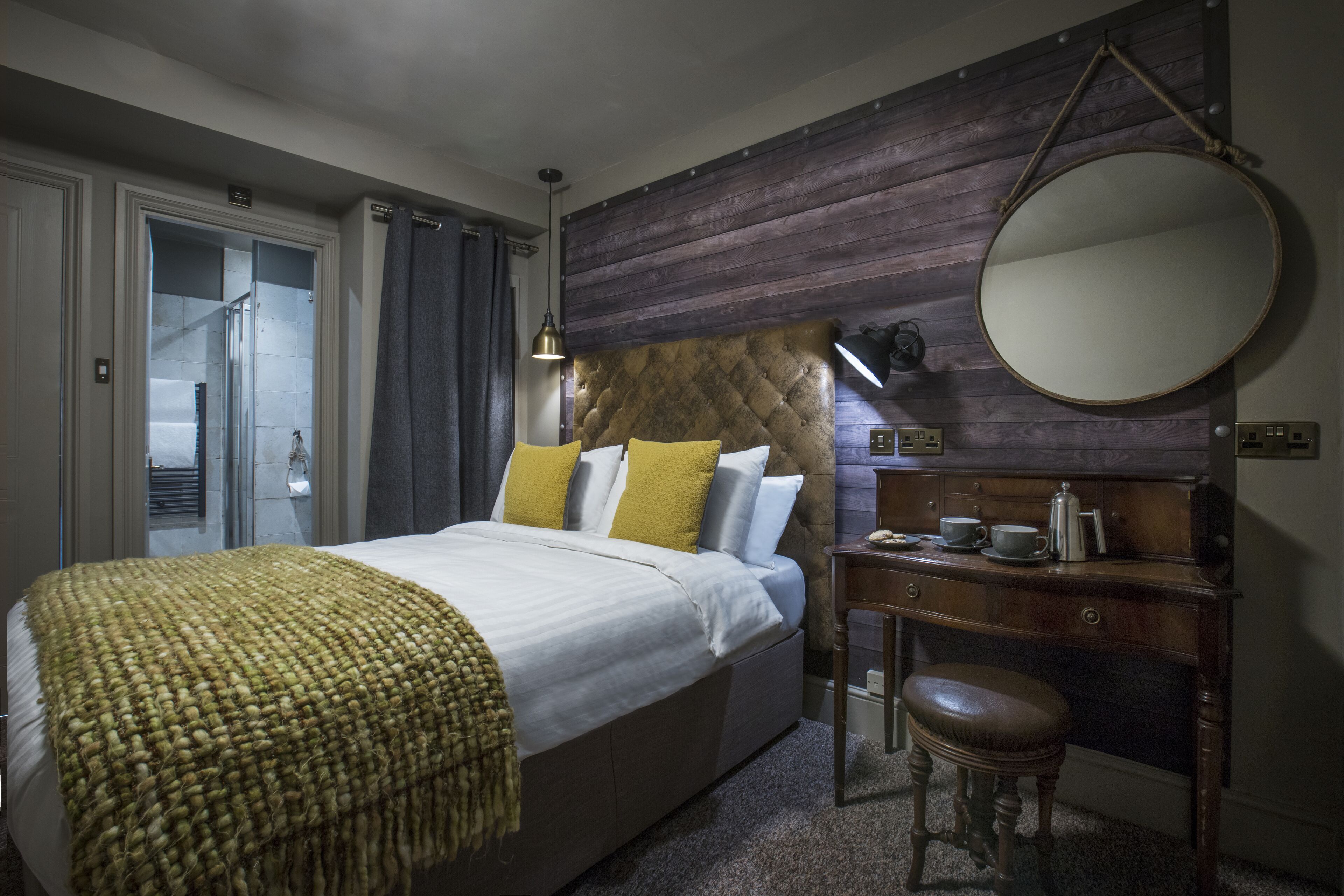A bedroom with a bed, bedside table, and a mirror.