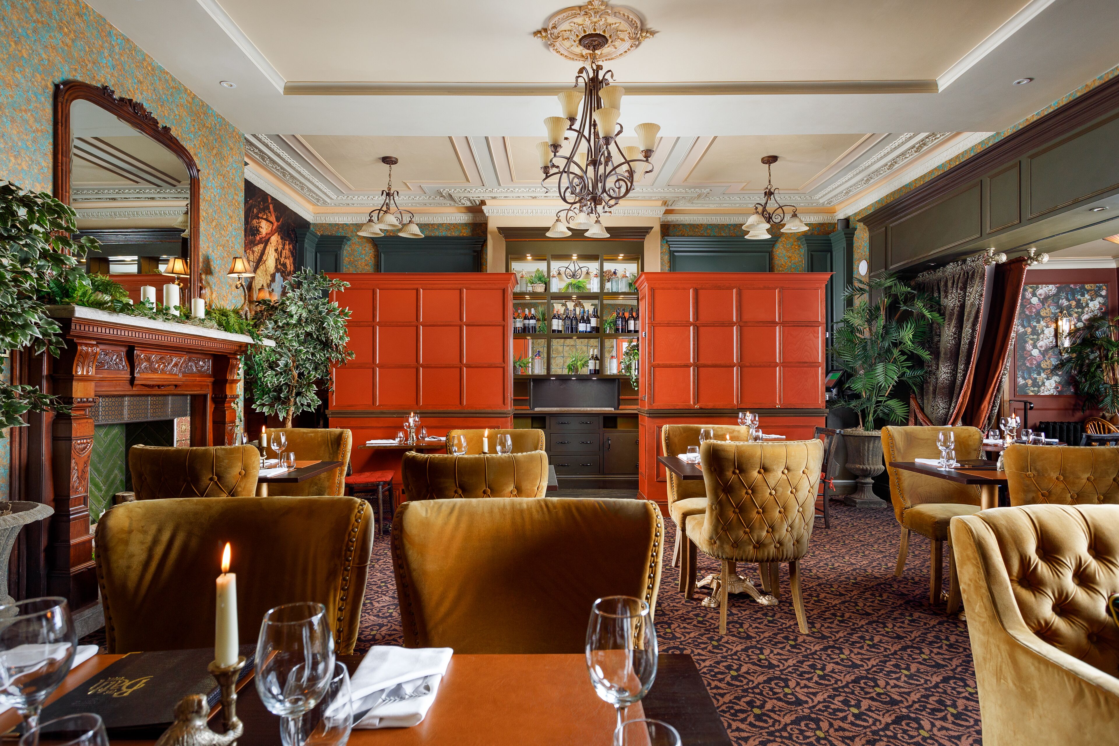Un comedor con sillas de terciopelo, chimenea y zona de bar con estantes llenos de botellas.