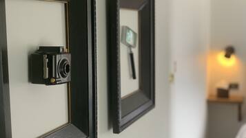 Duas fotografias emolduradas numa parede, uma de uma câmara fotográfica e outra de um espelho.
