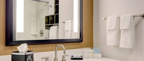 A modern bathroom with a large mirror, white sink, and towel rack.