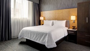 A hotel room with a large bed, two bedside tables with lamps, a wardrobe, and a view of the city through sheer curtains. - Hampton Inn Brooklyn/Downtown (Brooklyn)