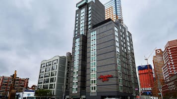 A multi-story hotel with a prominent 'Hampton Inn' sign, surrounded by other buildings and construction activity.