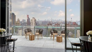 A balcony with a city view, furnished with chairs and tables, and a glass railing. - Hampton Inn Brooklyn/Downtown (Brooklyn)