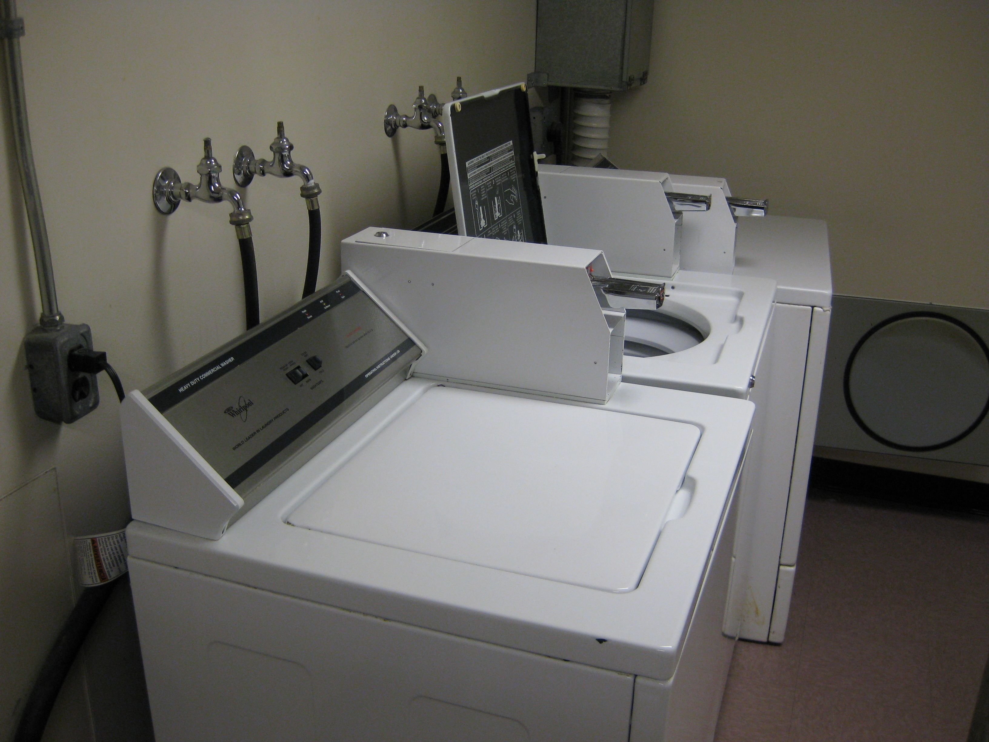 A laundry room with a front-loading washer and dryer, a water heater, and a control panel.