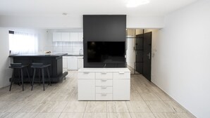 Een moderne keuken met witte kastjes, een zwart kookeiland met krukken en een groot zwart apparaat.