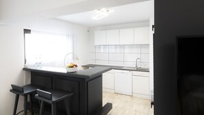 Een moderne keuken met witte kasten, een zwart aanrechtblad en een geïntegreerde vaatwasser.