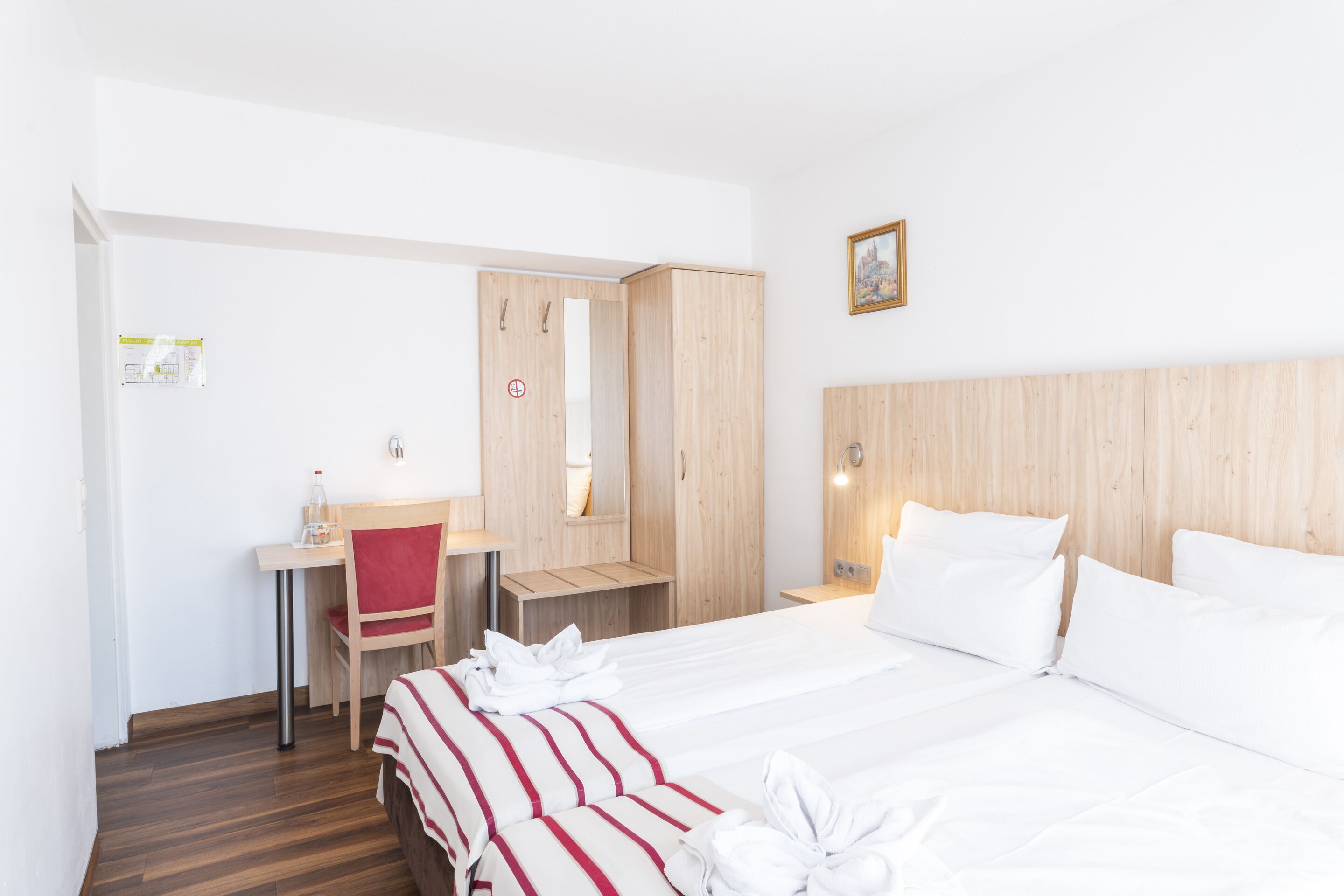 Une chambre d’hôtel comprenant un lit, un bureau, une chaise, une armoire et un miroir.