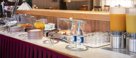 A buffet setup with various food items, beverages, and glassware.