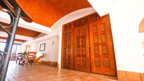 Un hall d’entrée spacieux avec un sol carrelé, une grande porte en bois ornée de sculptures complexes et un escalier menant aux étages supérieurs.