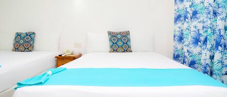 Habitación de hotel con dos camas, una mesita de noche y una cortina estampada.