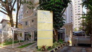 The entrance of Fenix Hotel with a clear pathway leading to the main building, surrounded by trees and a covered walkway. - Fenix Moema (São Paulo)