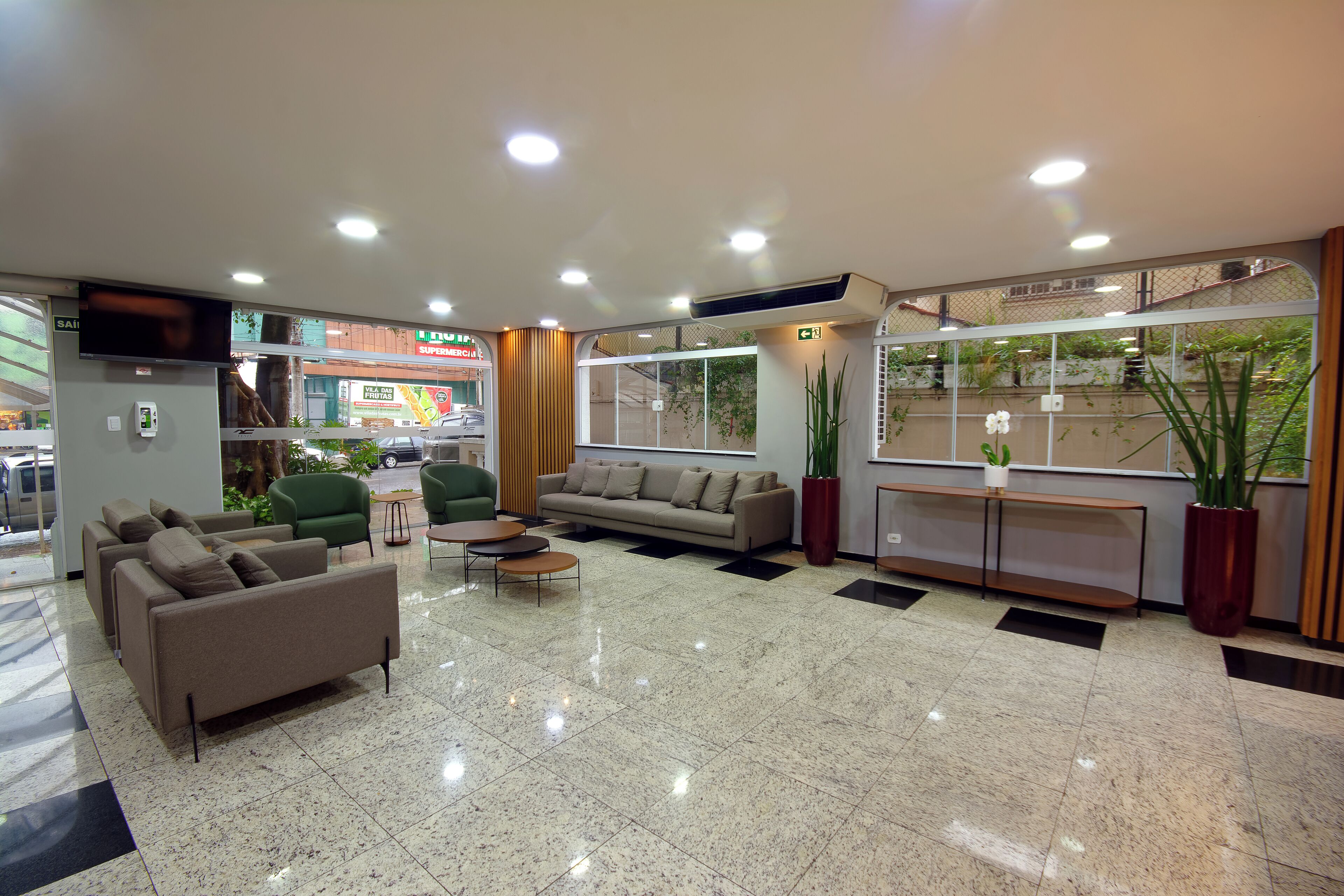 A lobby with a sofa, chairs, a coffee table, and potted plants.