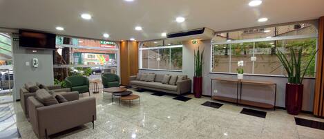A lobby with a sofa, chairs, a coffee table, and potted plants.