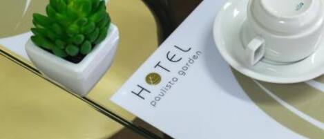 A hotel sign with the name "HOTEL poulisso garden" and a small potted plant on a table.