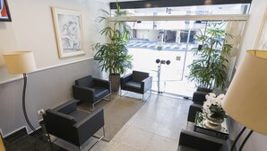 A reception area with black sofas, a potted plant, and a framed artwork on the wall. - Paulista Garden Hotel (São Paulo)
