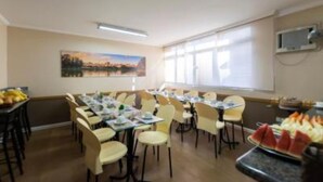 A dining area with tables set for meals, a painting on the wall, and a buffet with fruits. - Paulista Garden Hotel (São Paulo)