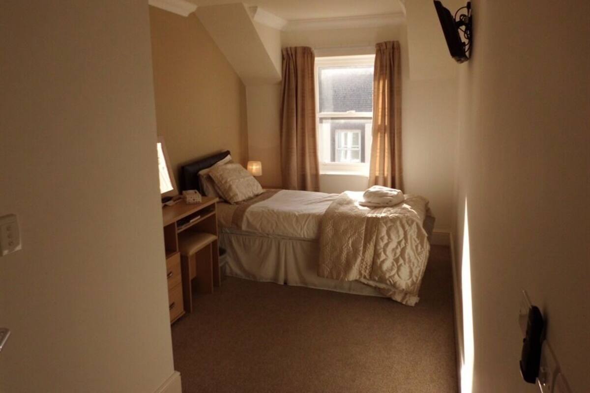 A bedroom with a bed, bedside table, and a window with curtains.