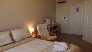 Una habitación de hotel con una cama, una silla, un escritorio y una puerta.