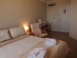 Una habitación de hotel con una cama, una silla, un escritorio y una puerta.