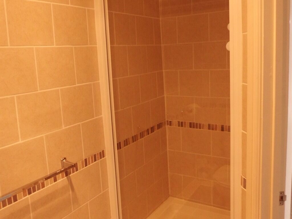 Un baño con azulejos color beige y ducha en esquina.
