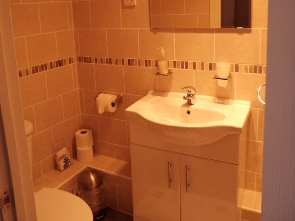 A bathroom with a sink, toilet, and shower area.