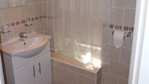Un baño con lavamanos, espejo y cortina de ducha.