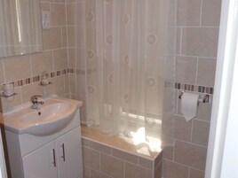 A bathroom with a sink, mirror, and shower curtain.