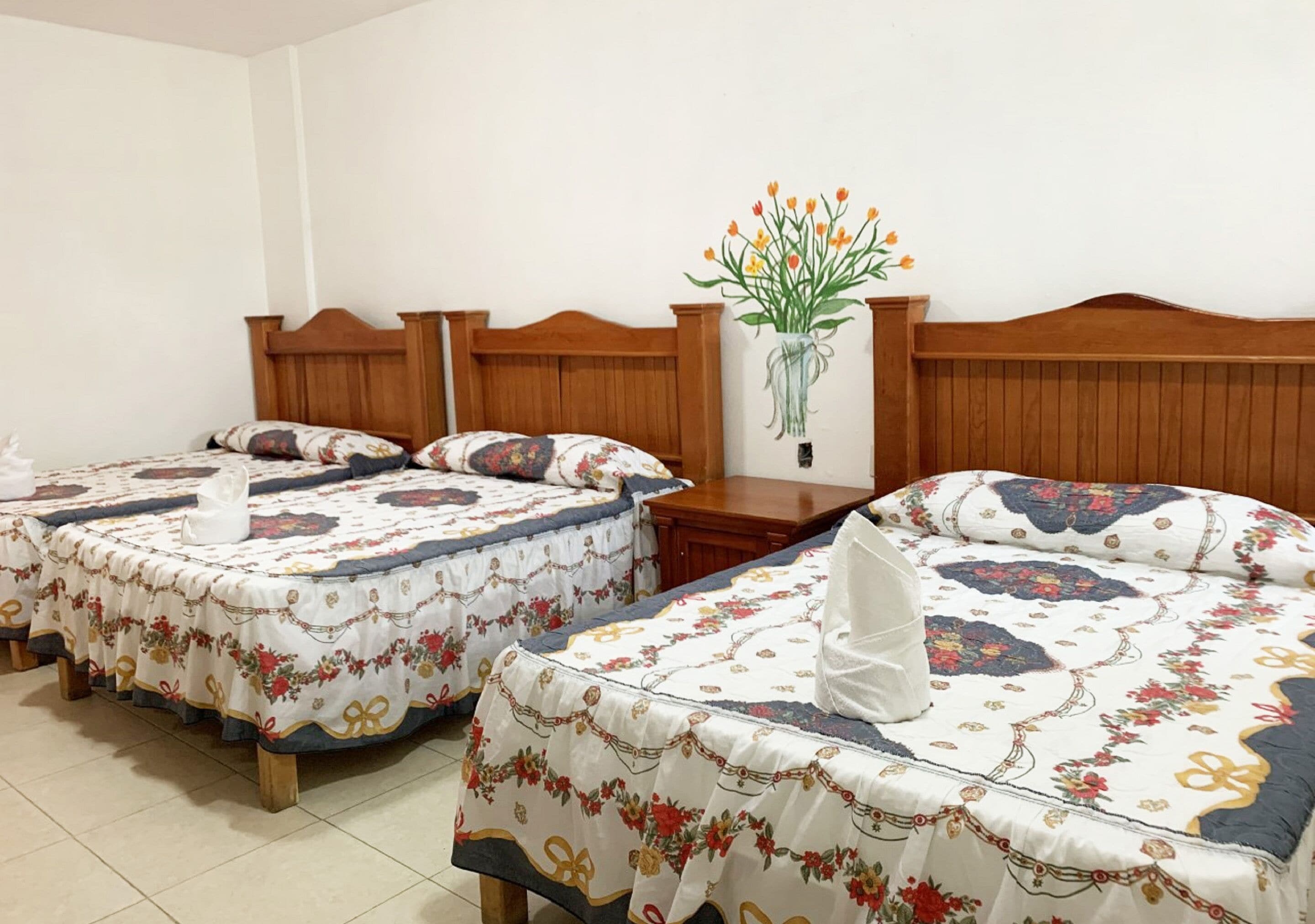 Habitación de hotel con dos camas, cada una con ropa de cama de diseño floral y cabeceros de madera.