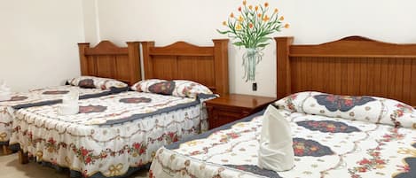 Habitación de hotel con dos camas, cada una con ropa de cama de diseño floral y cabeceros de madera.