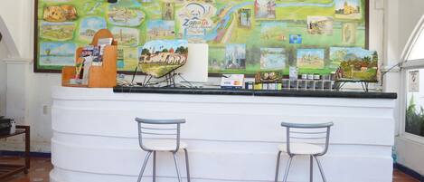 A bar area with a mural, two bar stools, and a counter with a Visa sign.