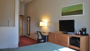 A hotel room with a bed, desk, chair, television, and a painting on the wall. - The Soluna Hotel (El Paso)
