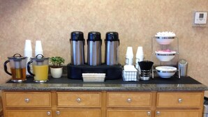A kitchen counter with coffee makers, cups, and a small potted plant. - The Soluna Hotel (El Paso)