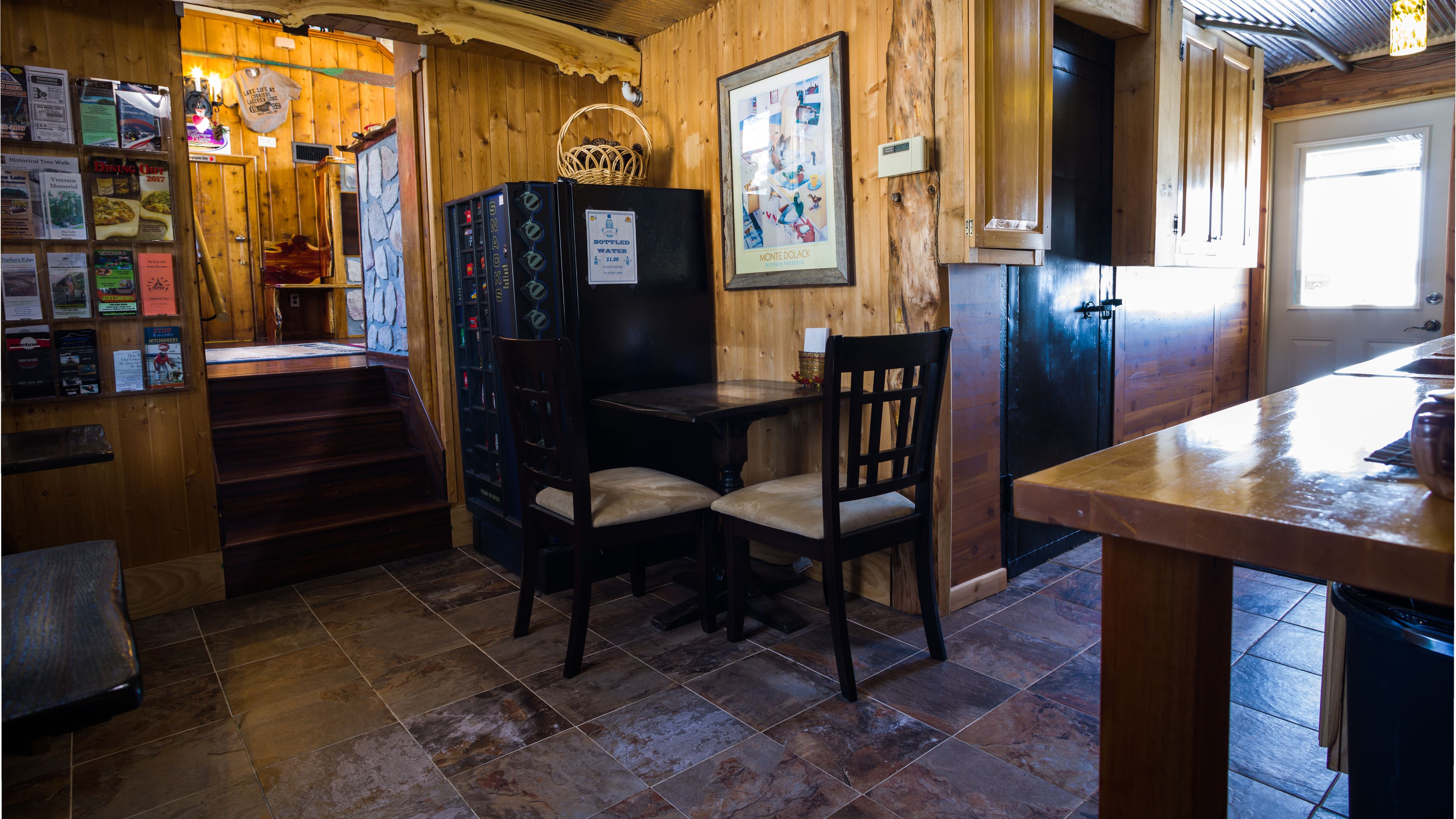 Un intérieur en bois comprenant un coin bar, une table à manger et un escalier menant à un mur en pierre.