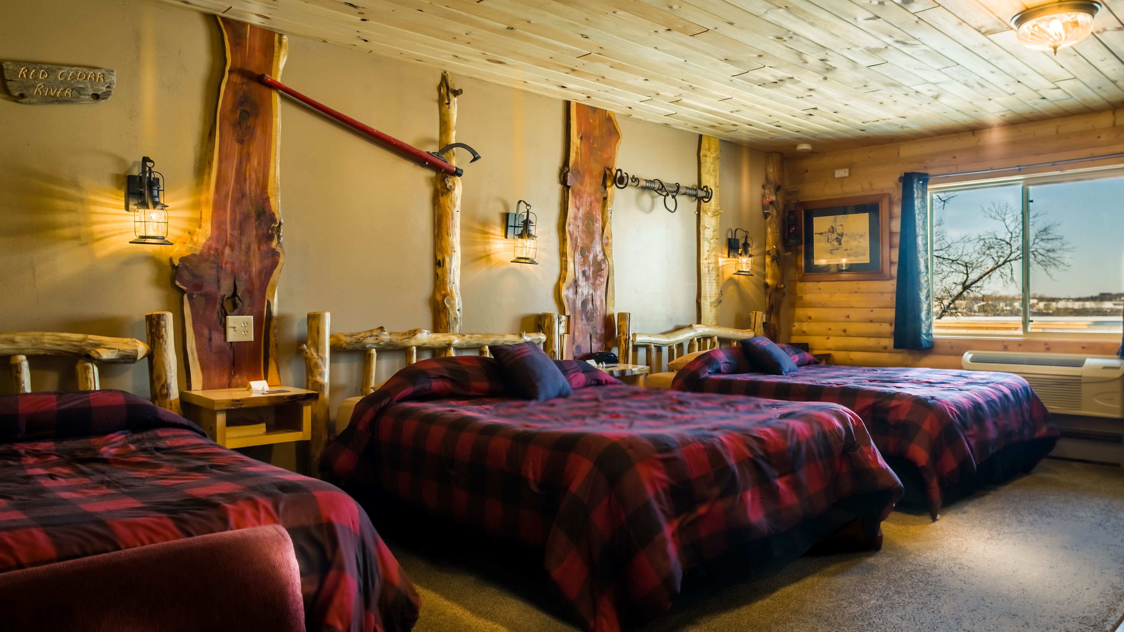 A cabin-style room with two beds, rustic wooden decor, and a view of the outside.